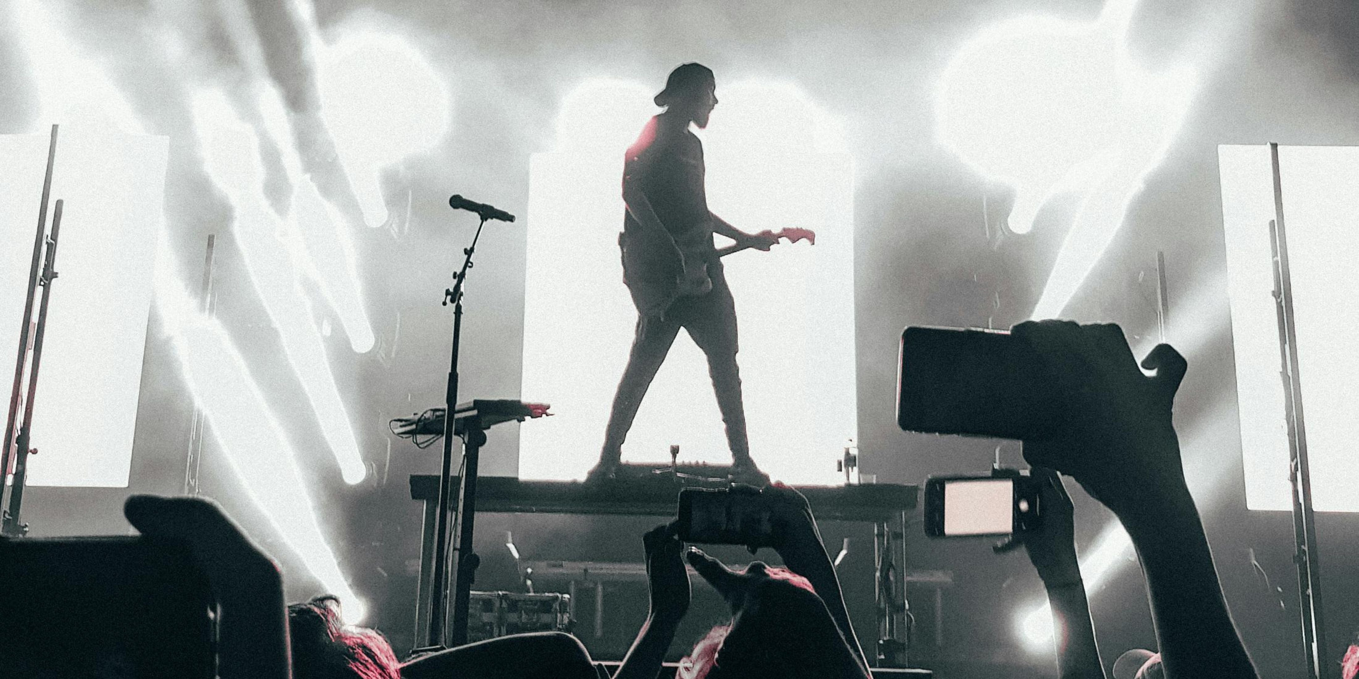 A musician is playing a guitar on stage in front of a crowd