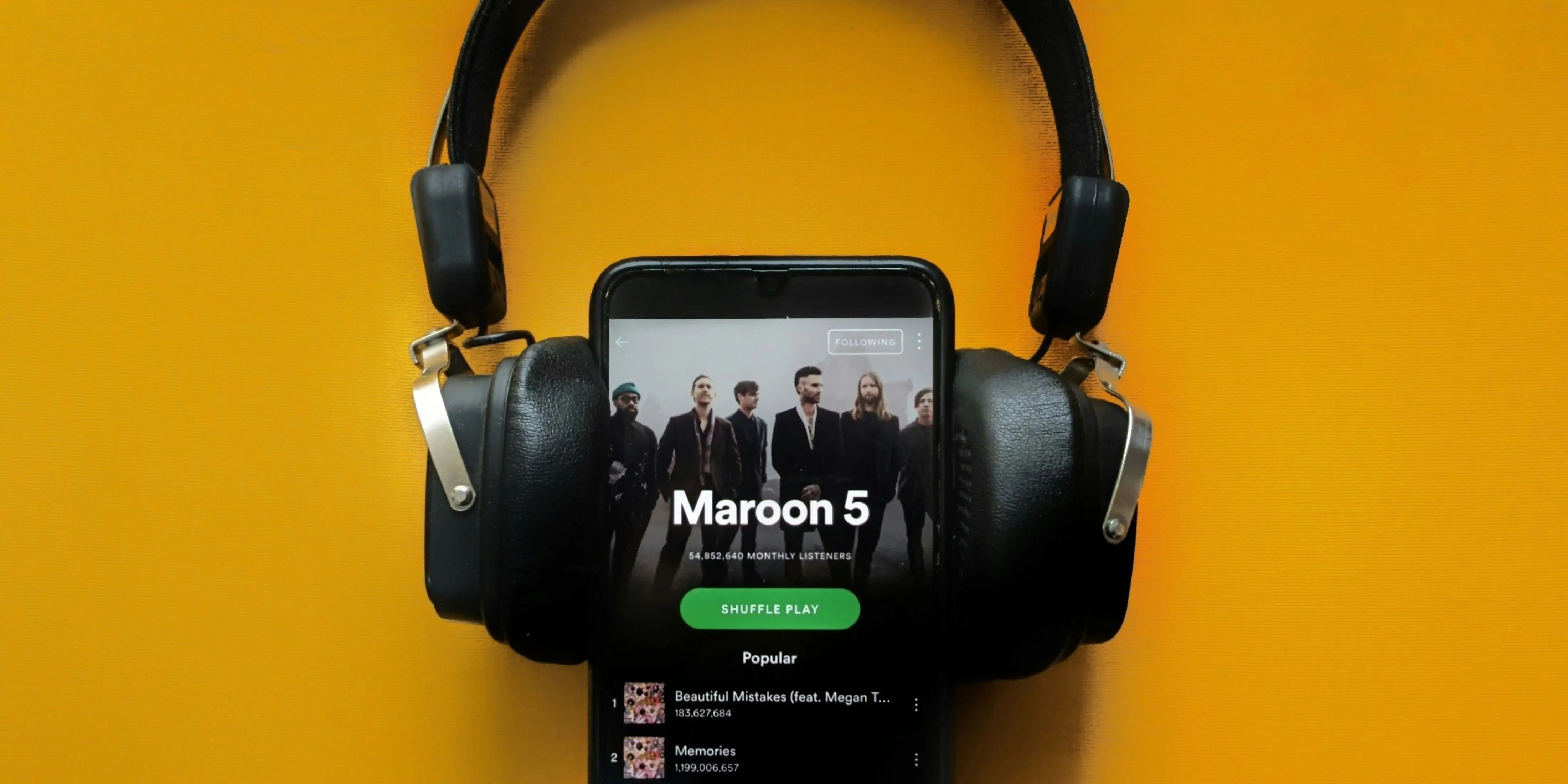 The Maroon 5 Spotify page appears on a smartphone with headphones around it