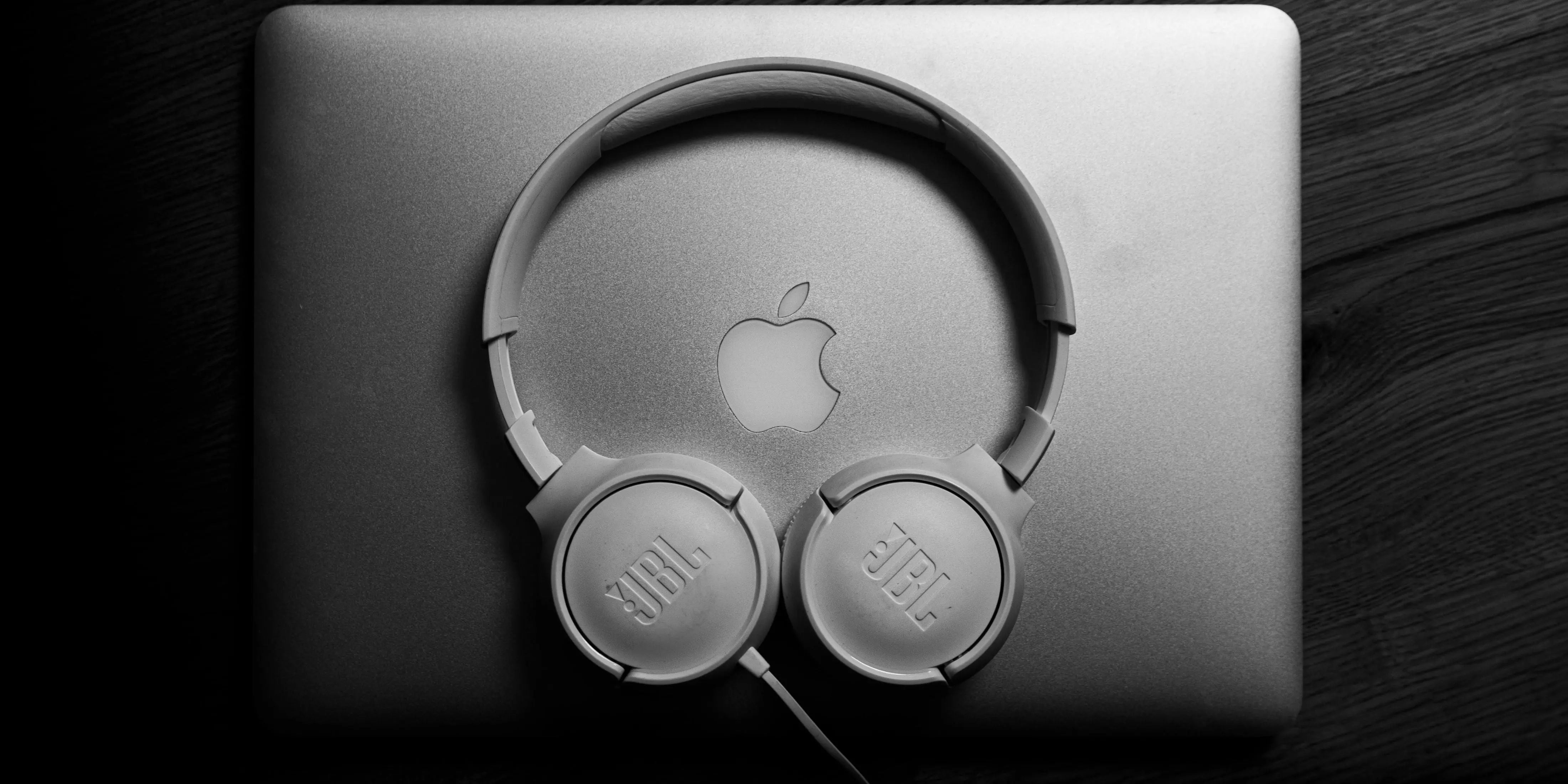 JBL headphones are placed on top of a gray MacBook device