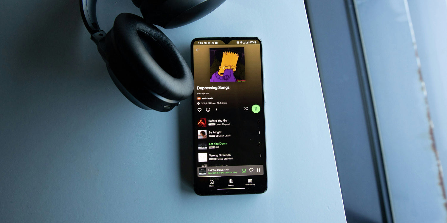 The Spotify app is shown on a mobile phone with headphones around it. 