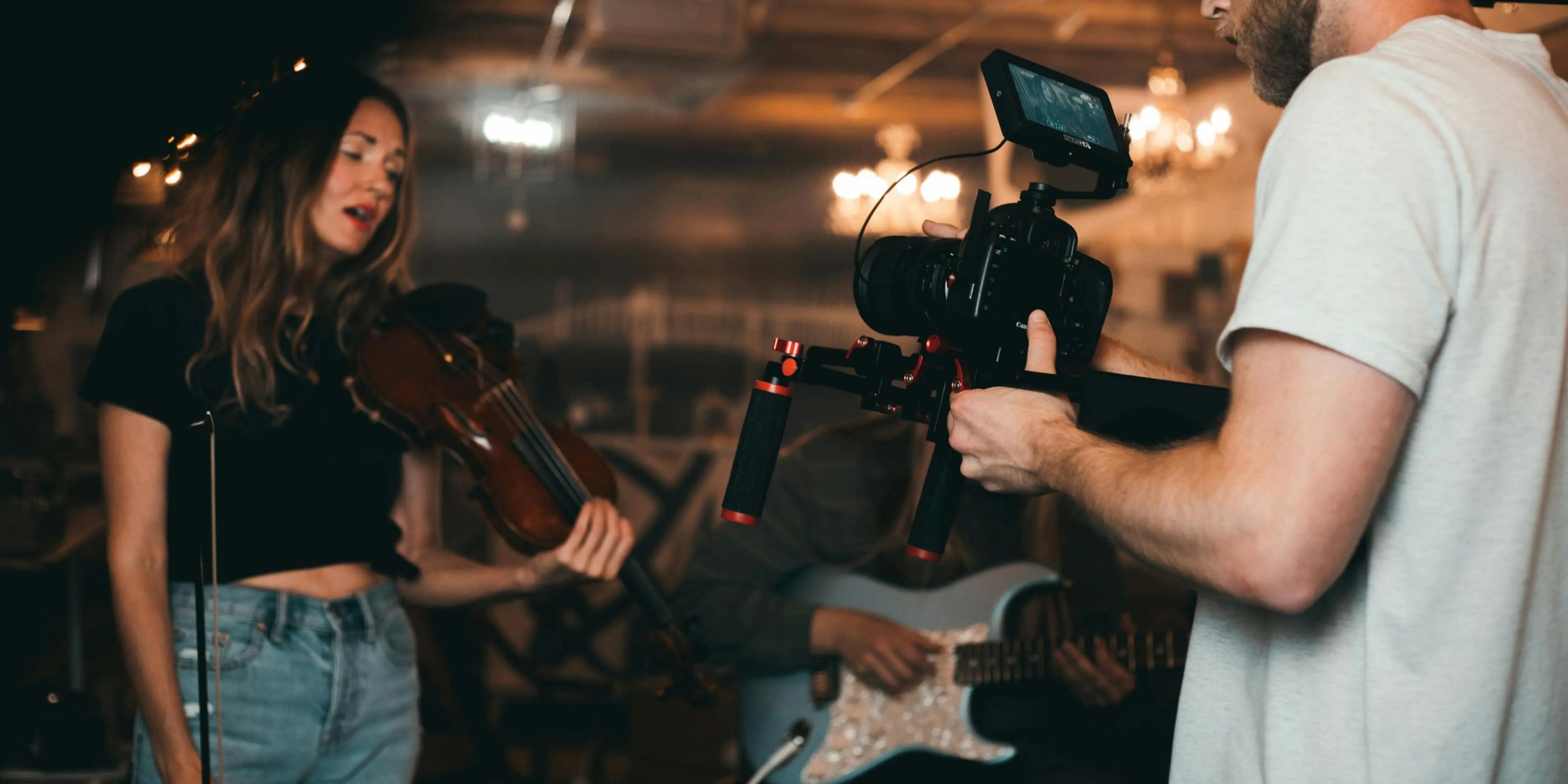 A videographer is recording a musician playing the guitar